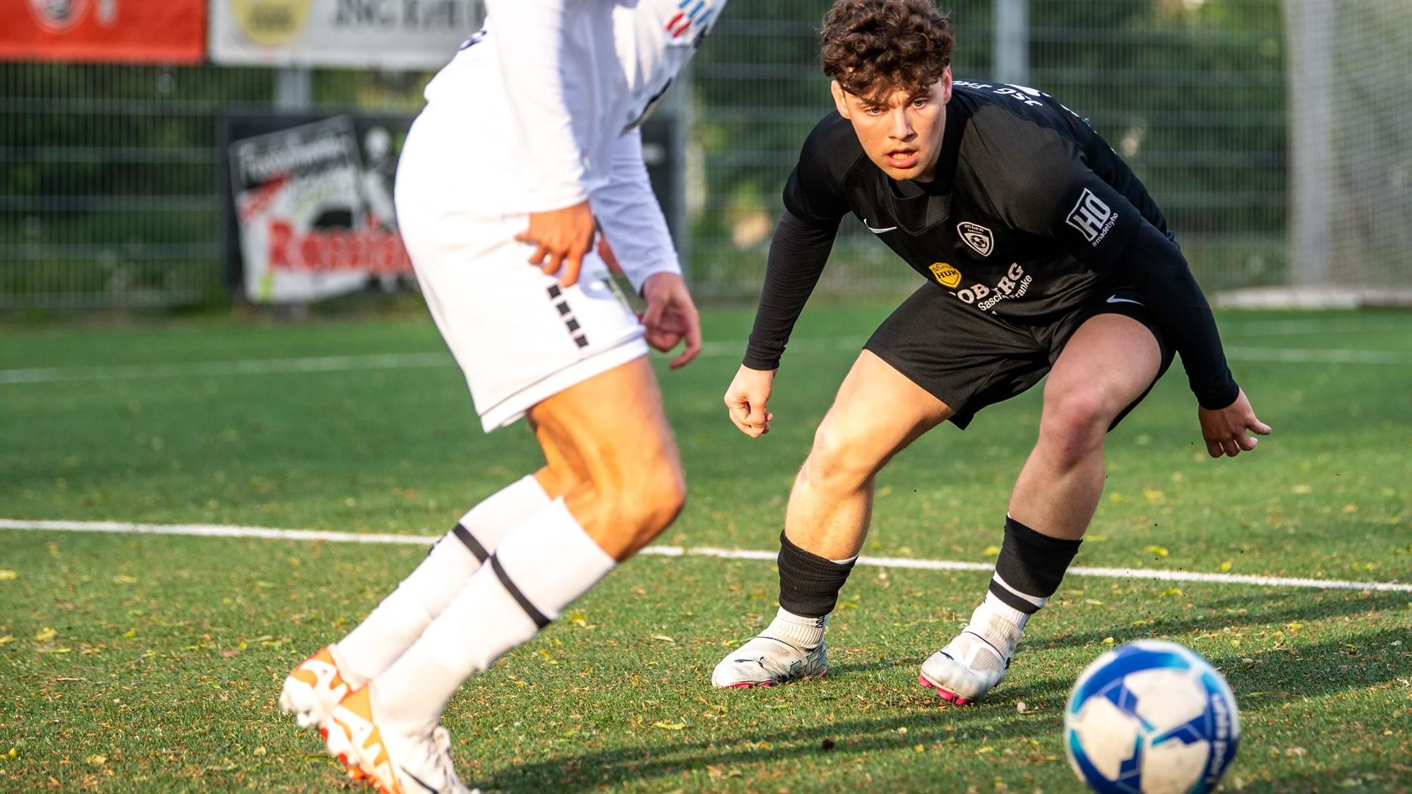 Ein Fußballspieler schaut gebannt auf einen Ball, der von einem Gegenspieler geführt wird.