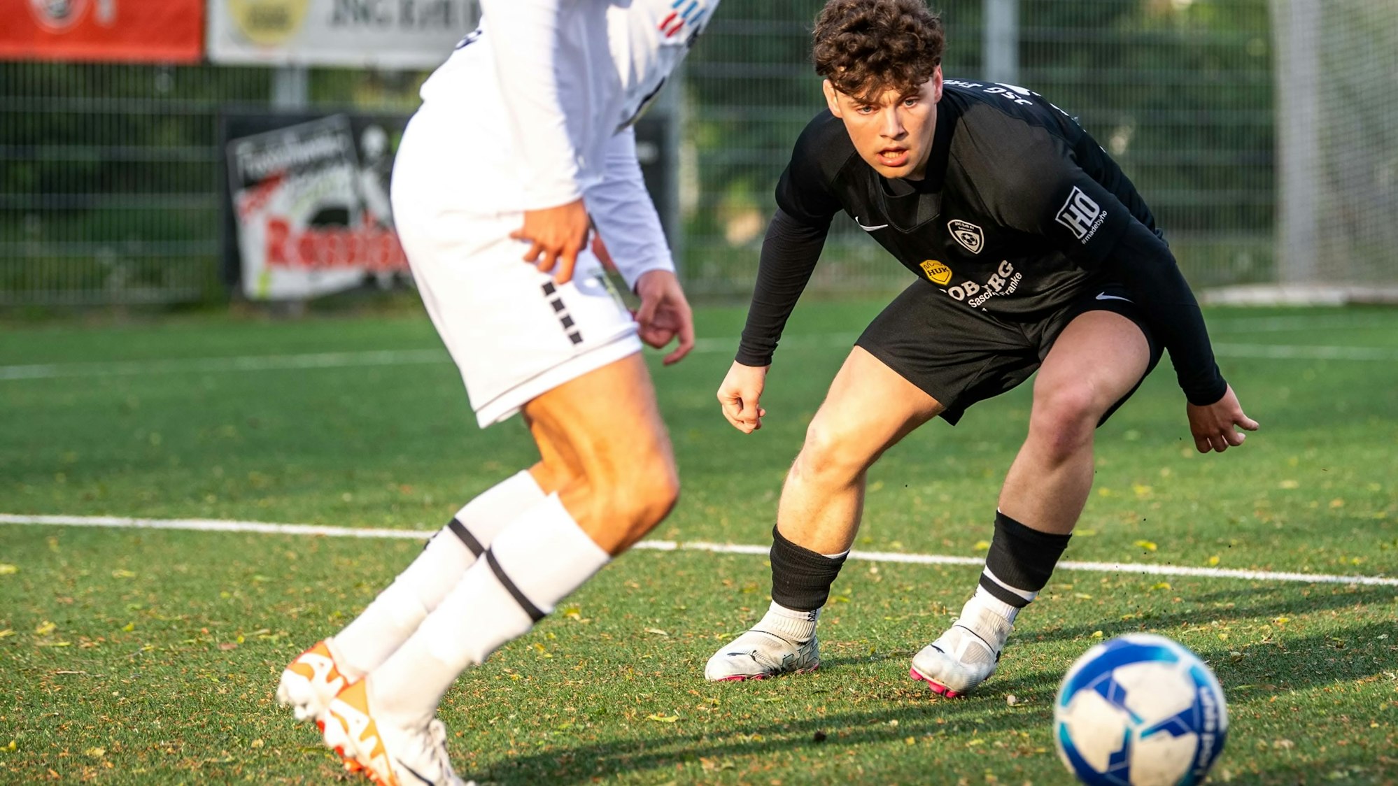 Ein Fußballspieler schaut gebannt auf einen Ball, der von einem Gegenspieler geführt wird.