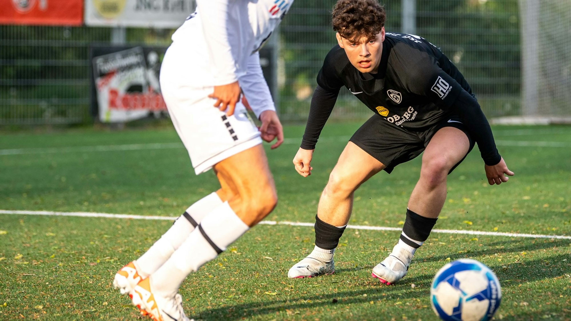 Ein Fußballspieler schaut gebannt auf einen Ball, der von einem Gegenspieler geführt wird.