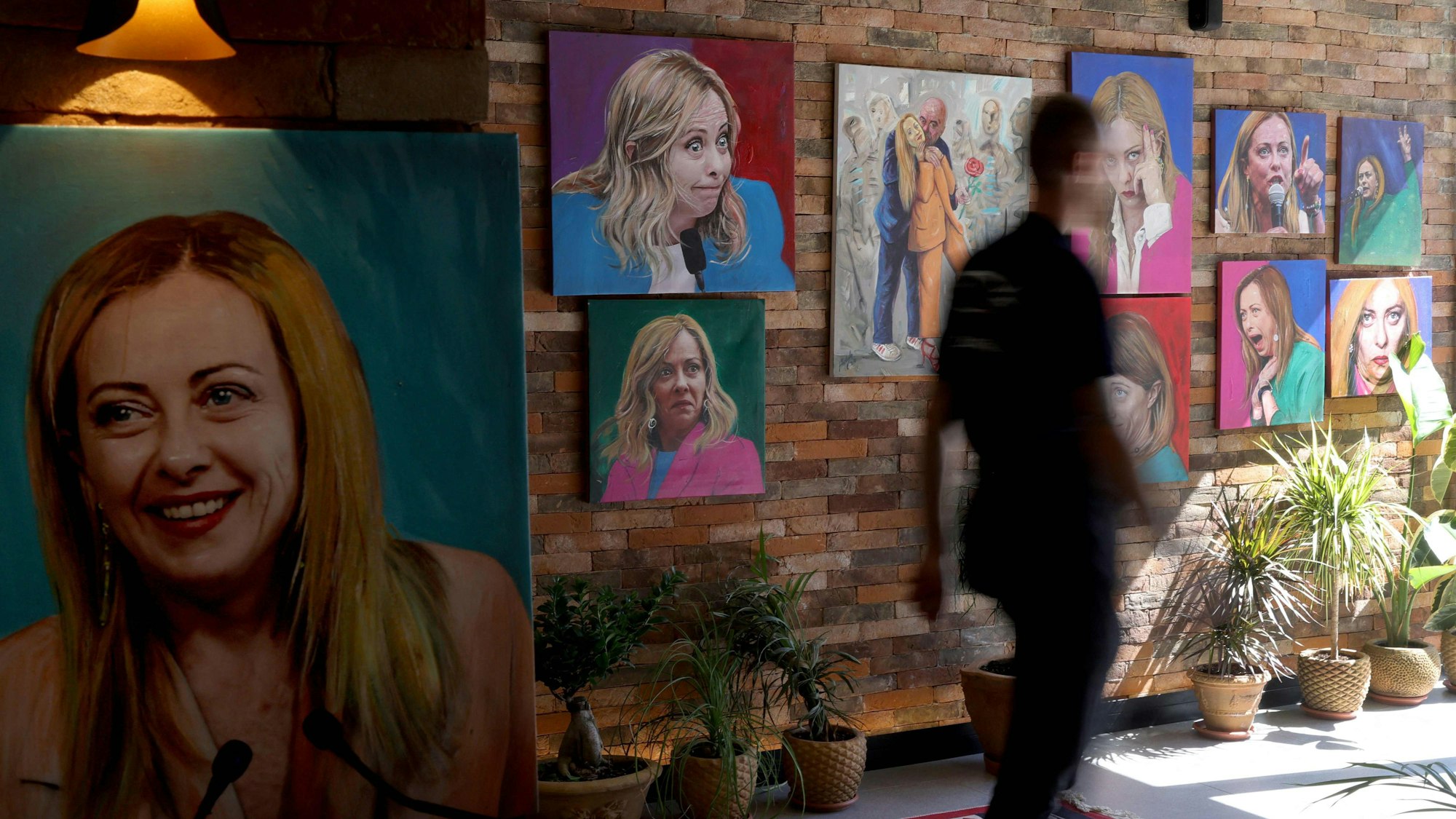 Ein Gast geht am 23. September 2024 an Porträts der italienischen Ministerpräsidentin Giorgia Meloni vorbei, die die Wand des Restaurants „Trattoria Meloni“ in Shengjin, etwa 60 km nordwestlich von Tirana, zieren.