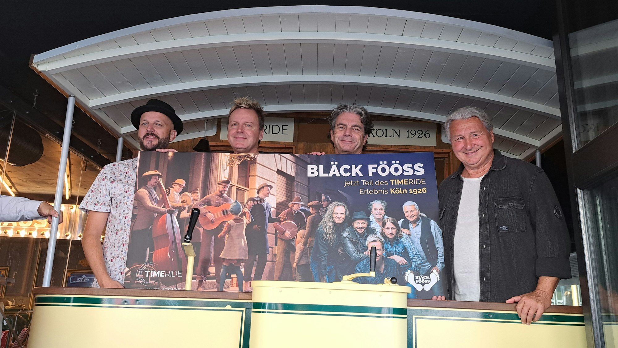 Die Bläck Fööss stehen im historischen Eisenbahnwagen von Time Ride. Sie haben im aktuellen Film einen Auftritt als Straßenmusiker.