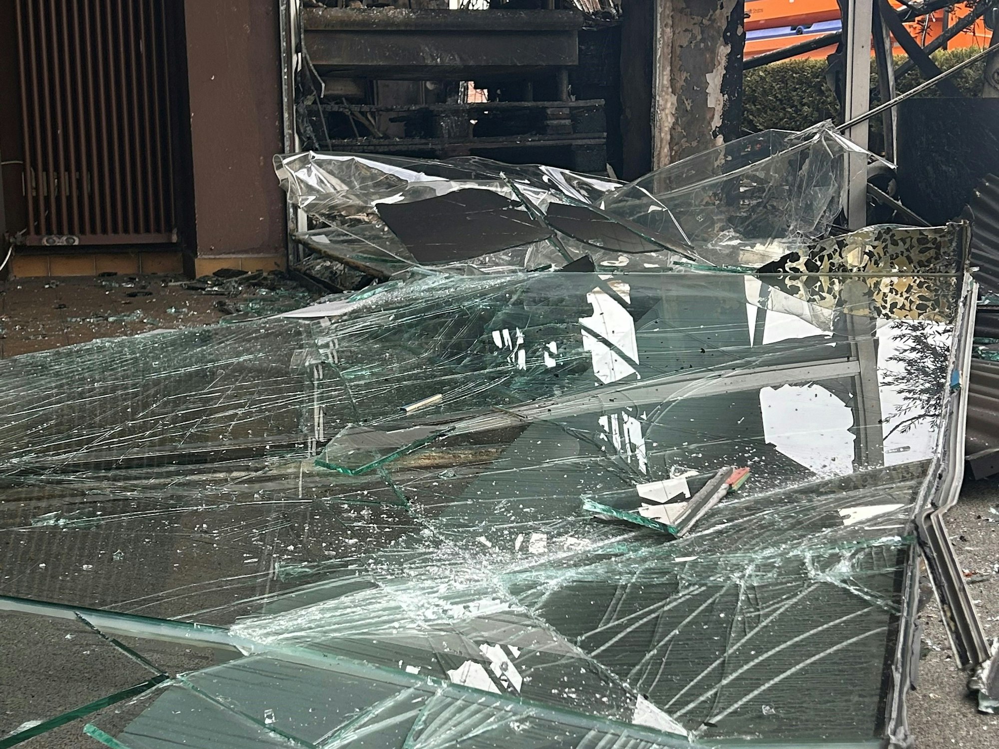 Glassplitter liegen am Tag nach der Explosion vor dem ausgebrannten Café in Longerich.