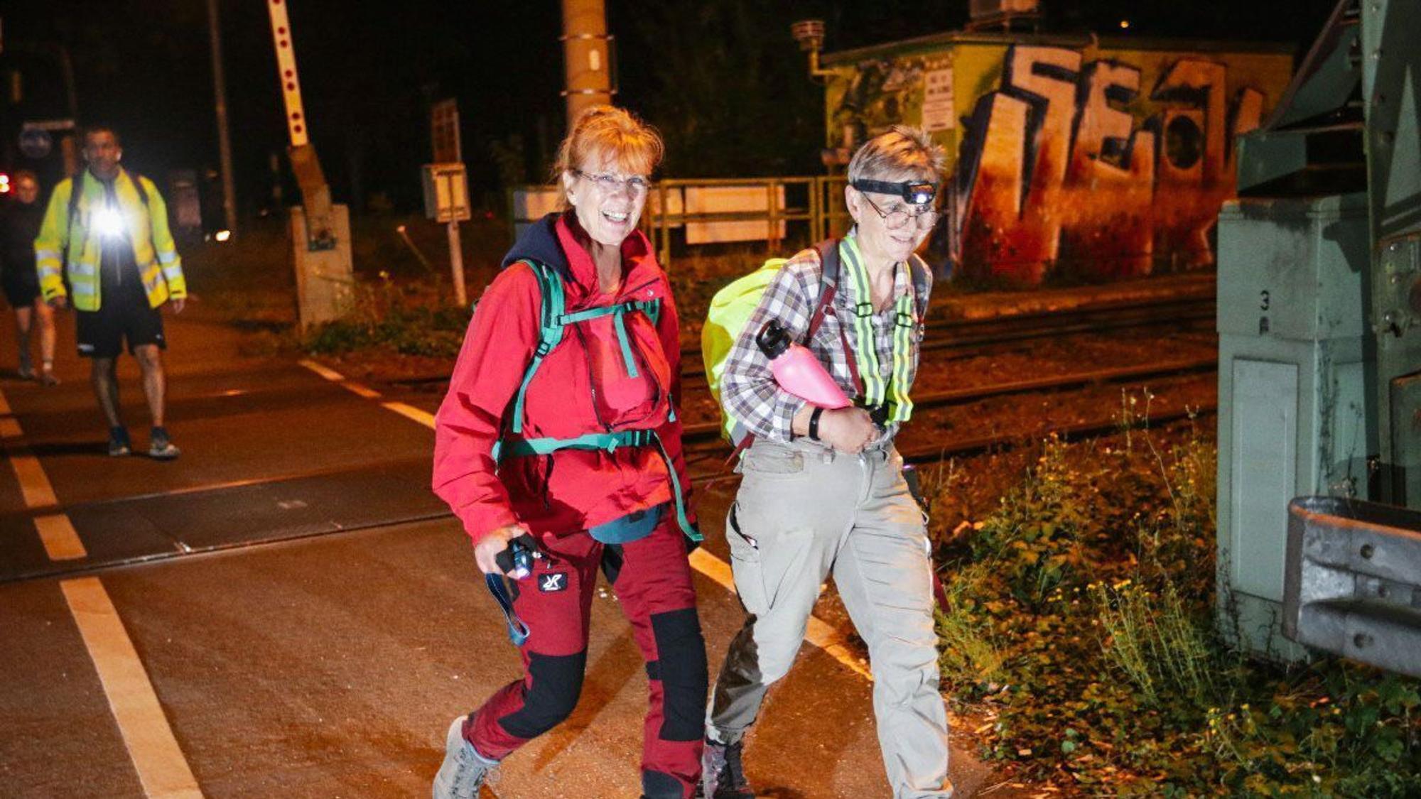 Zwei Frauen marschieren durch die nächtliche Stadt.