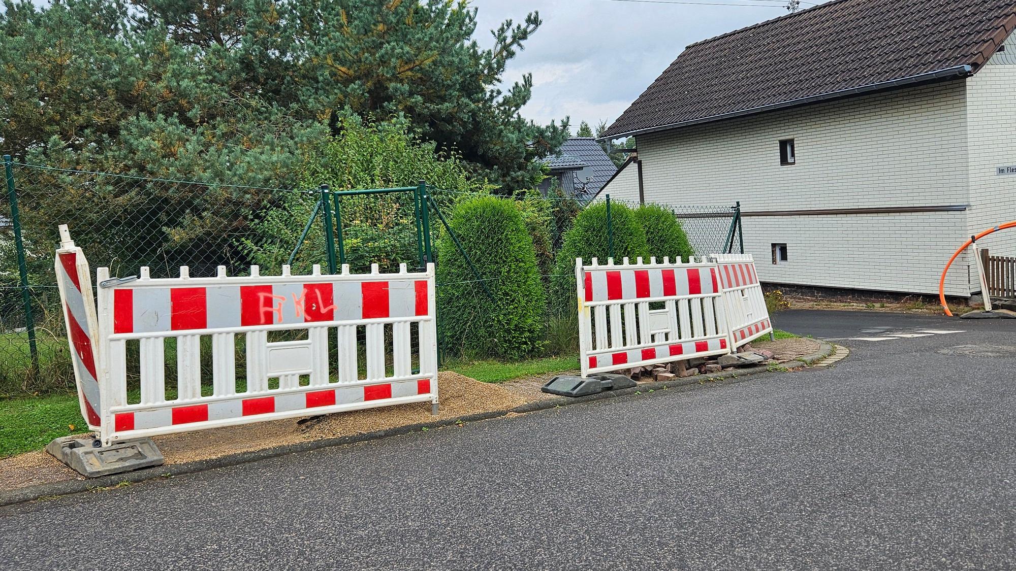 Blick auf mehrere Baken und Absperrgitter, die auf einem Gehweg stehen.