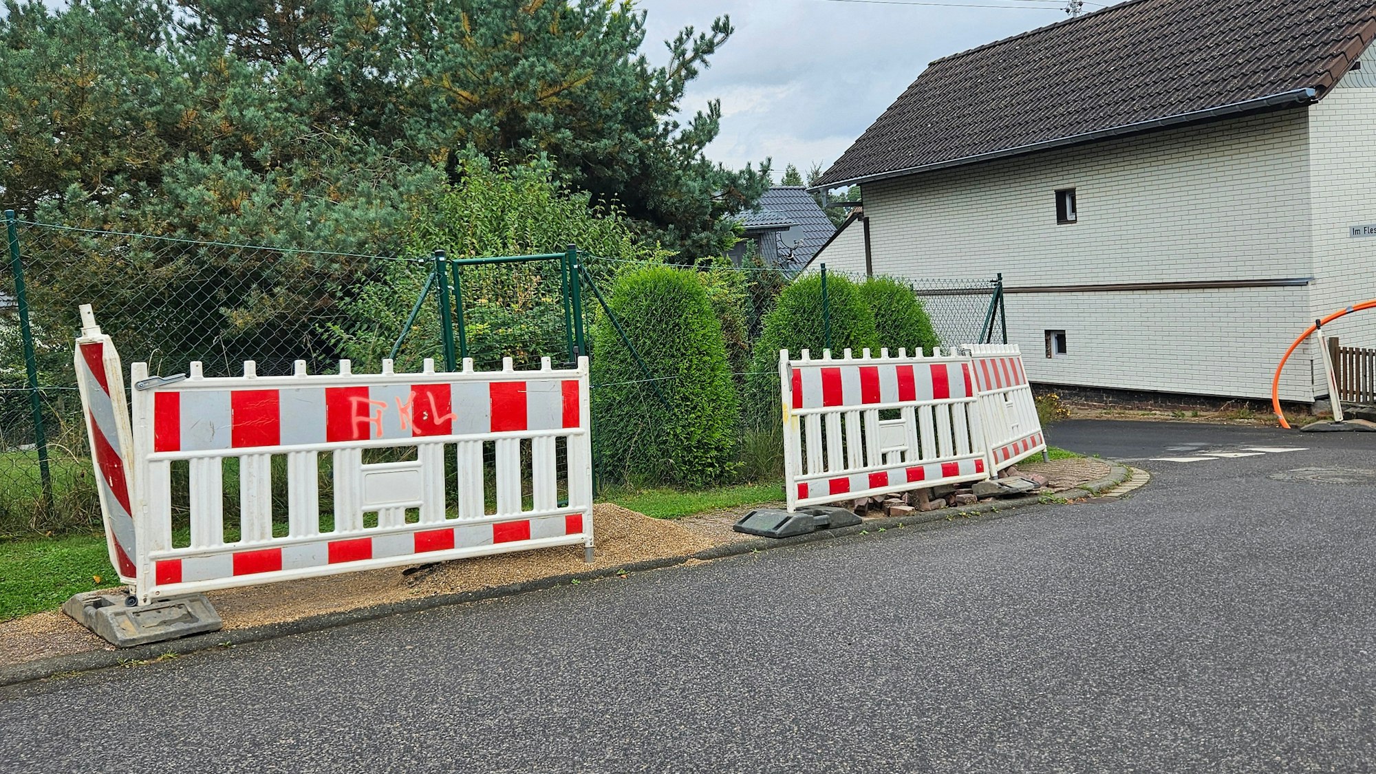 Blick auf mehrere Baken und Absperrgitter, die auf einem Gehweg stehen.
