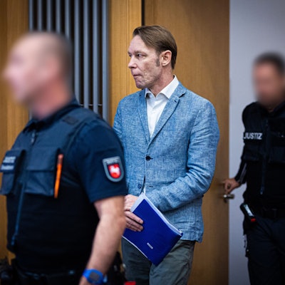 Der Angeklagte Christian B. (M) wird von Justizmitarbeitern in einen Gerichtssaal im Landgericht geführt.