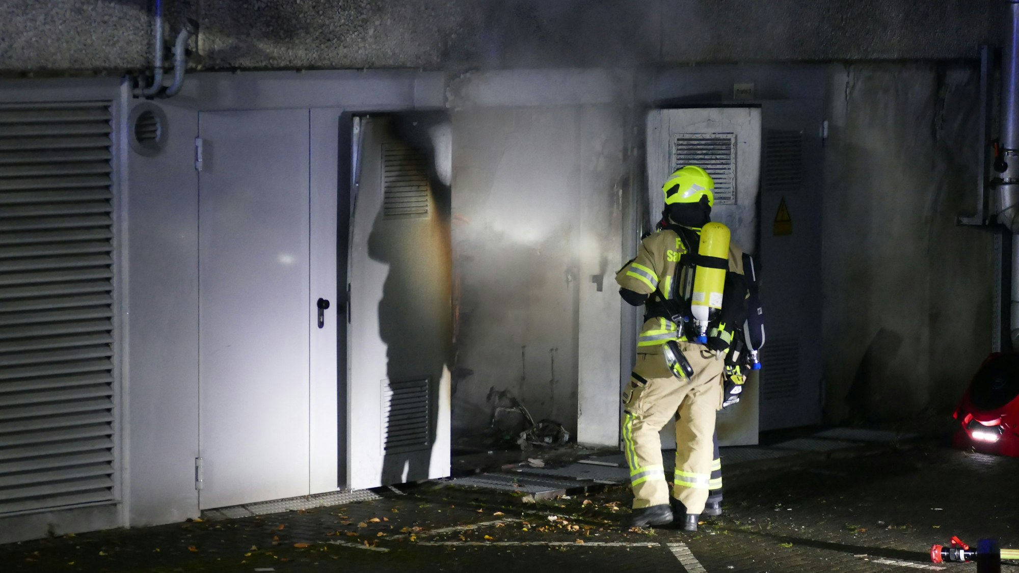 Ein Feuerwehrmann vor einer verrauchten Tür.