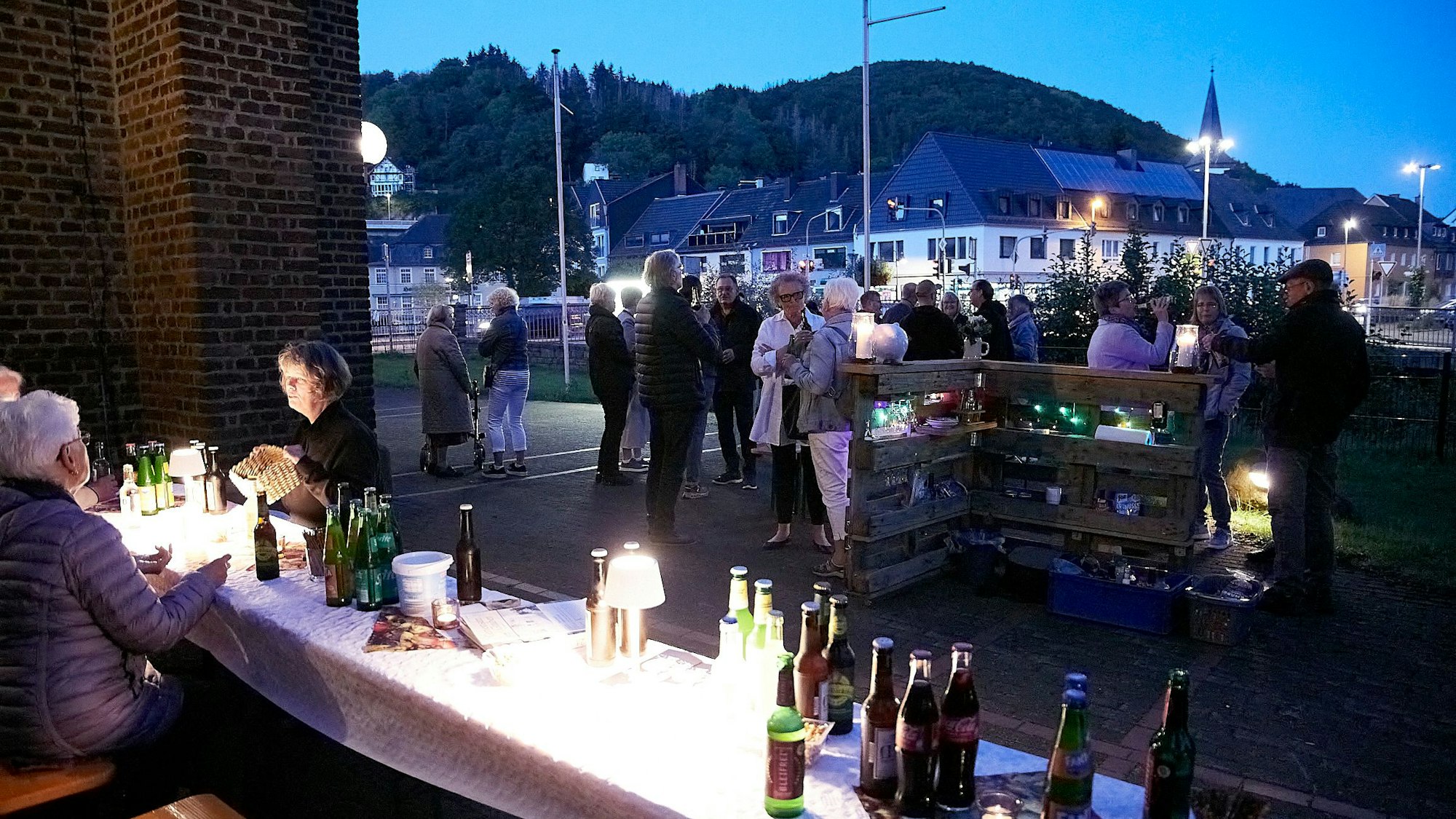 Menschen stehen miteinander im Gespräch vor der Kirche oder sitzen an Biertischen.