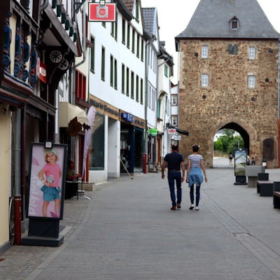 Zwei Menschen gehen nebeneinander durch die Orchheimer Straße in Bad Münstereifel in Richtung Orchheimer Tor.