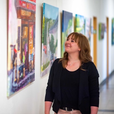 Das Bild zeigt Sabine Dünnwald, die im Flur des Rathauses steht und sich ein Bild anschaut.