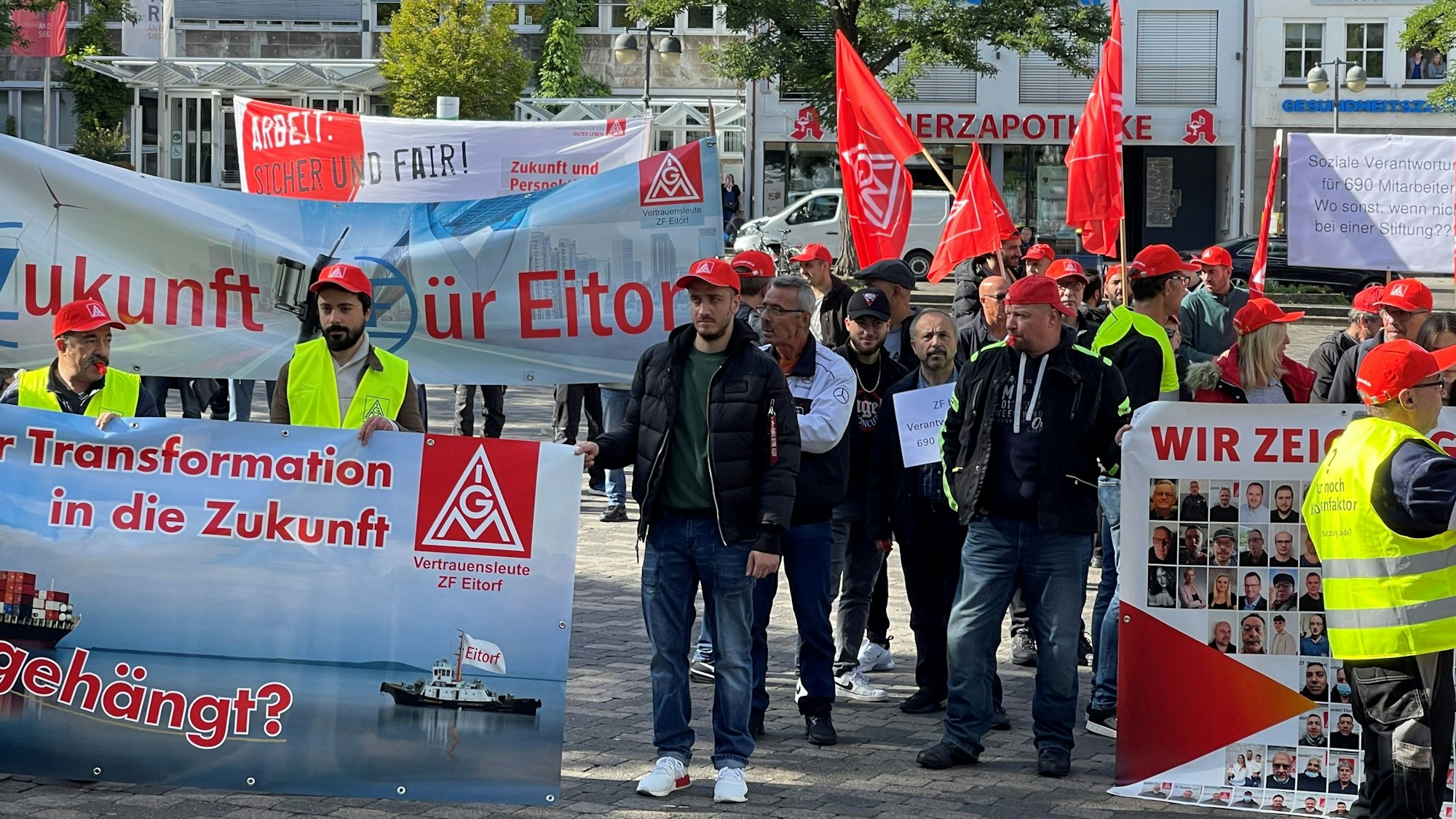 Demonstration von Menschen mit Plakaten, Kappen und Fahnen.