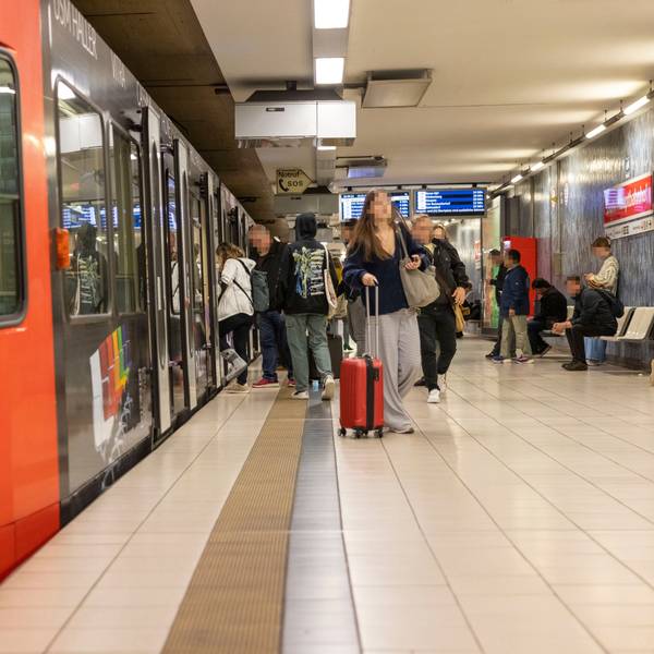 Leute steigen an einer Haltestelle aus einer Bahn.