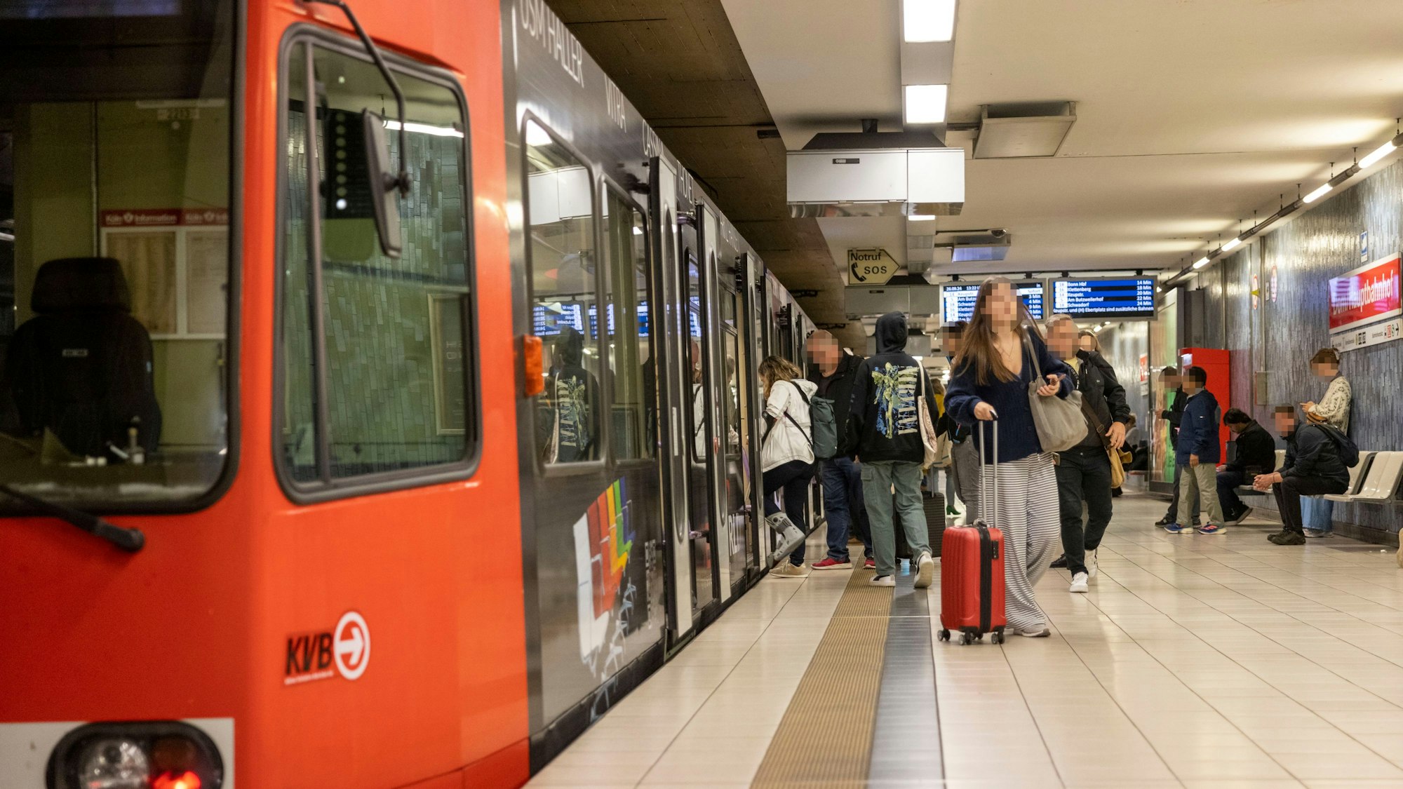 Leute steigen an einer Haltestelle aus einer Bahn.