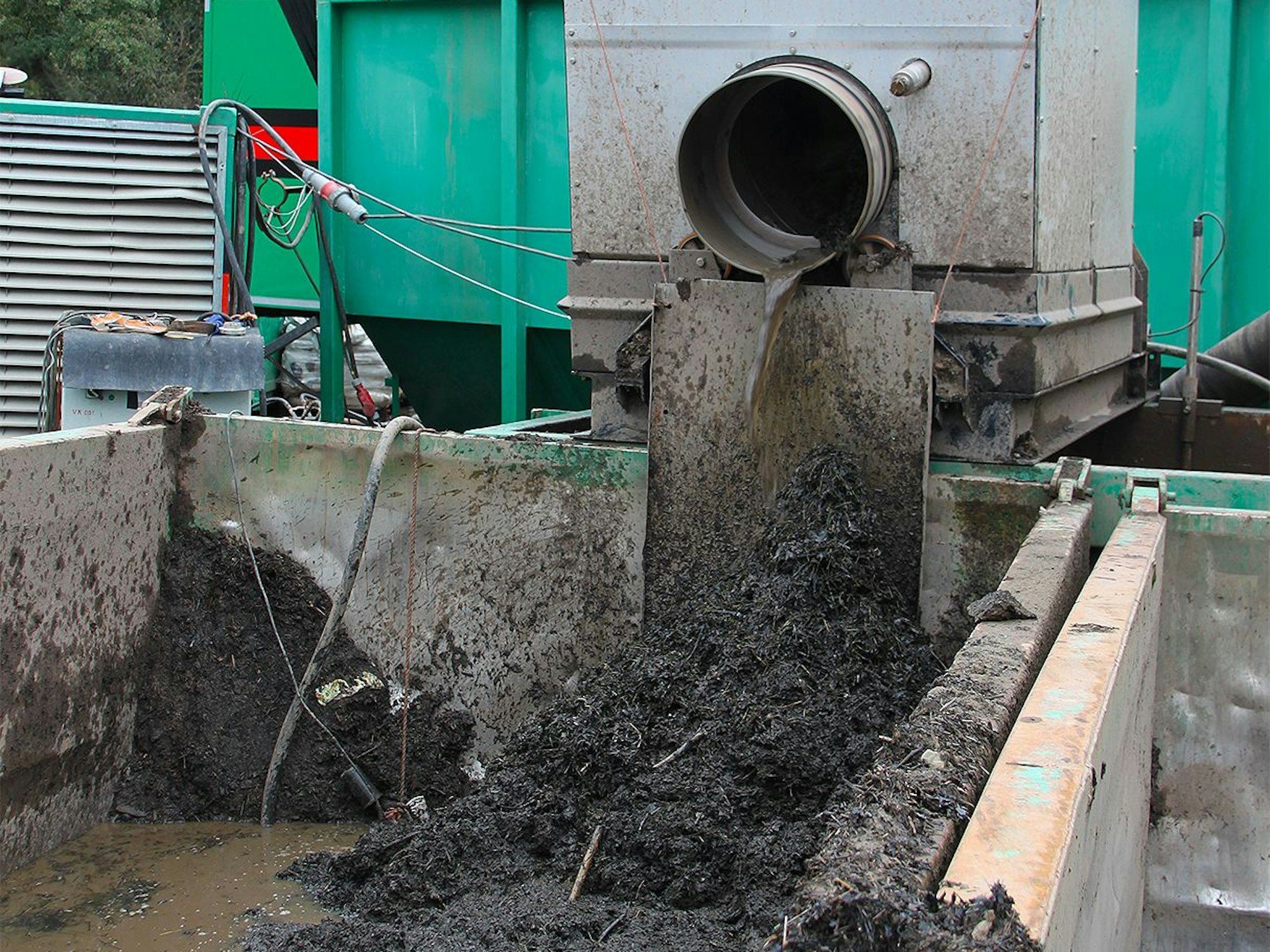 Ein Gemisch aus Wasser und Störstoffen fließt aus einem Rohr in einen Container.