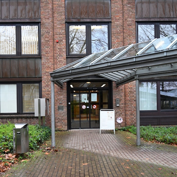 Zu sehen ist der überdachte Eingang eines Gebäudes aus Backstein.