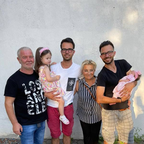 Zu sehen sind Zwillinge mit ihren Eltern sowie einem Mädchen und einem Baby auf dem Arm.
