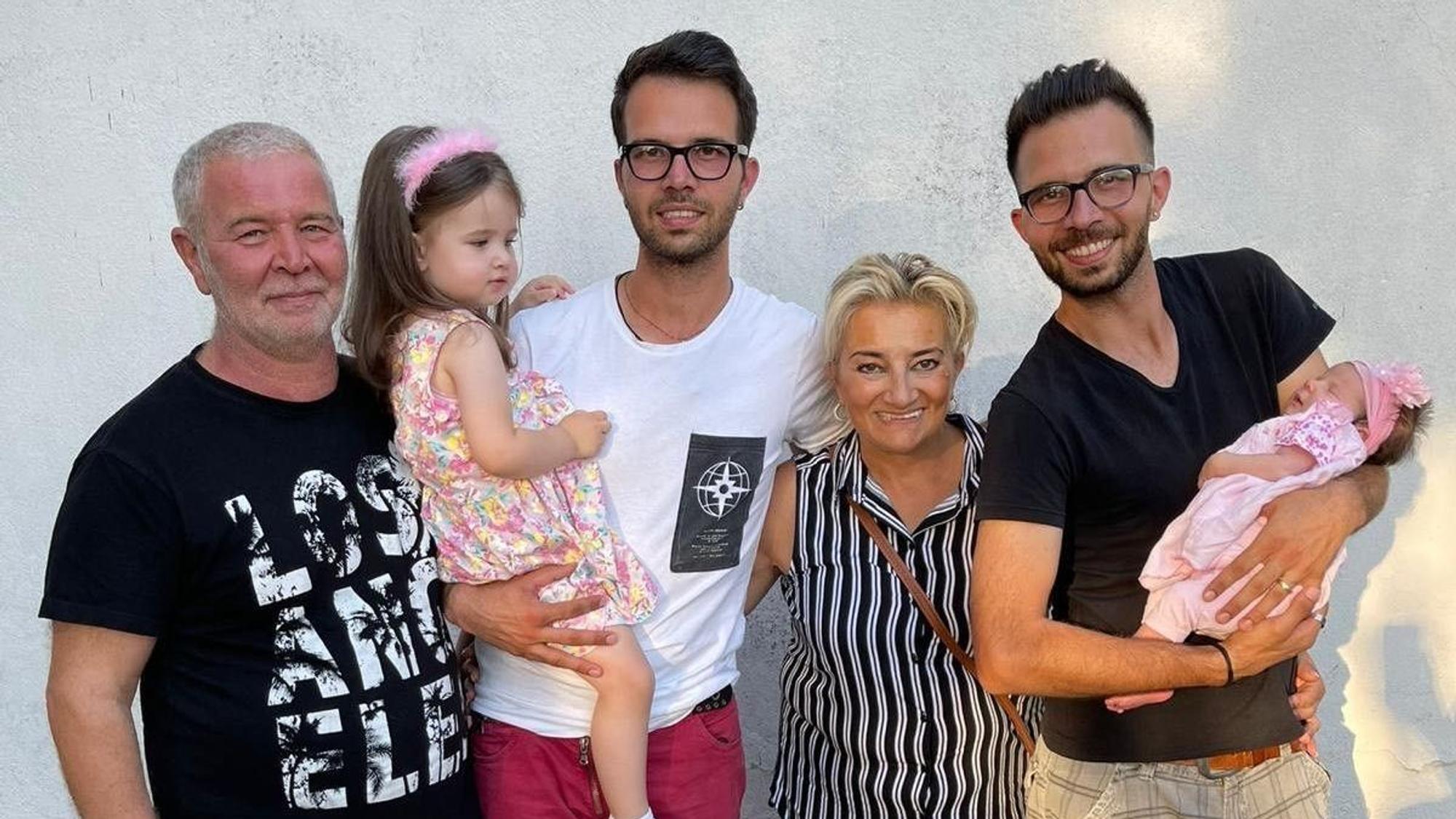 Zu sehen sind Zwillinge mit ihren Eltern sowie einem Mädchen und einem Baby auf dem Arm.