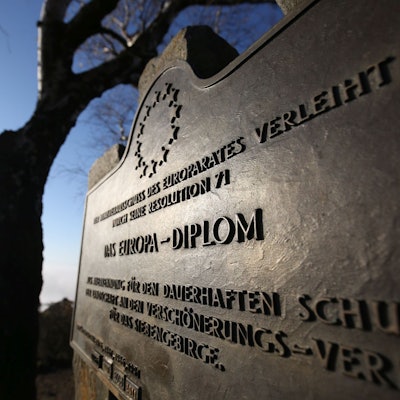 Eine Bronze-Platte mit der Aufschrift "Das Europa-Diplom", im Hintergrund ein Baum vor blauem Himmel.