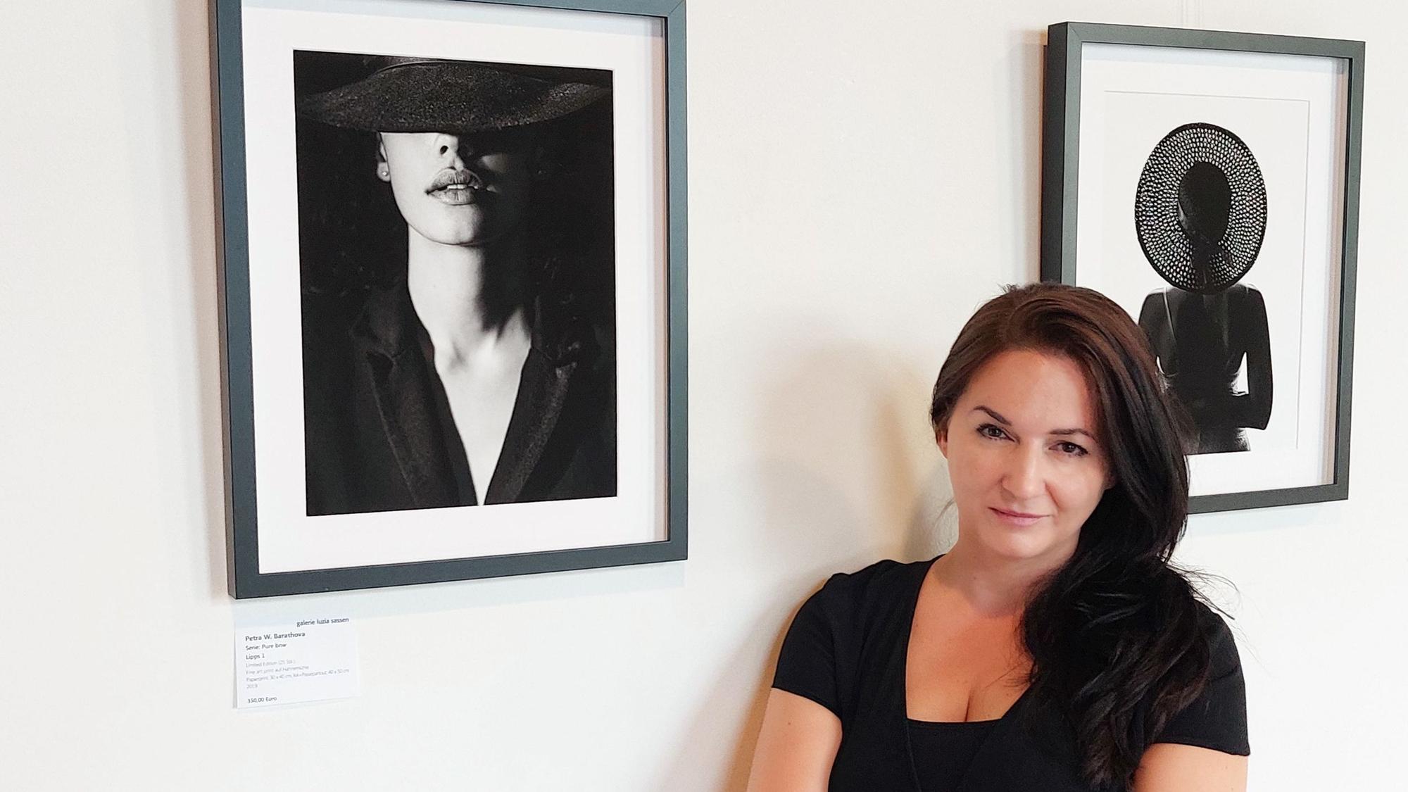 Künstlerin Petra W. Barathova steht in einer Ausstellung mit Schwarz-Weiß-Fotografien.