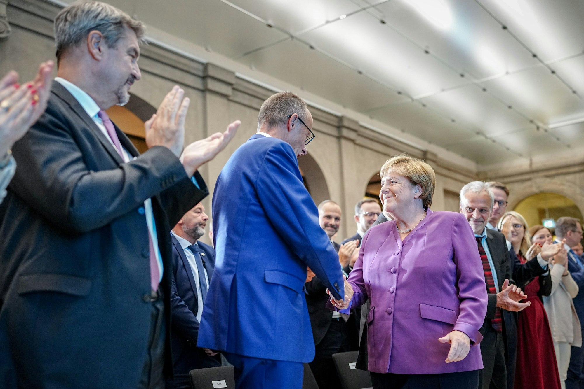 Angela Merkel und Friedrich Merz (M), CDU-Bundesvorsitzender und Unionsfraktionsvorsitzender, reichen sich neben Markus Söder (l), Ministerpräsident von Bayern und CSU-Vorsitzender, die Hand.