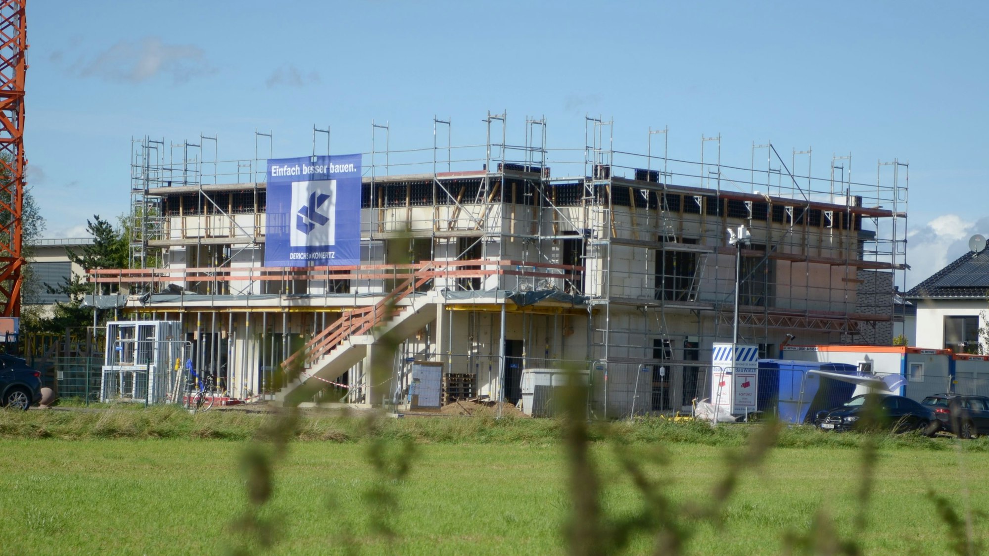 Blick über ein Ackergrundstück auf den Rohbau.