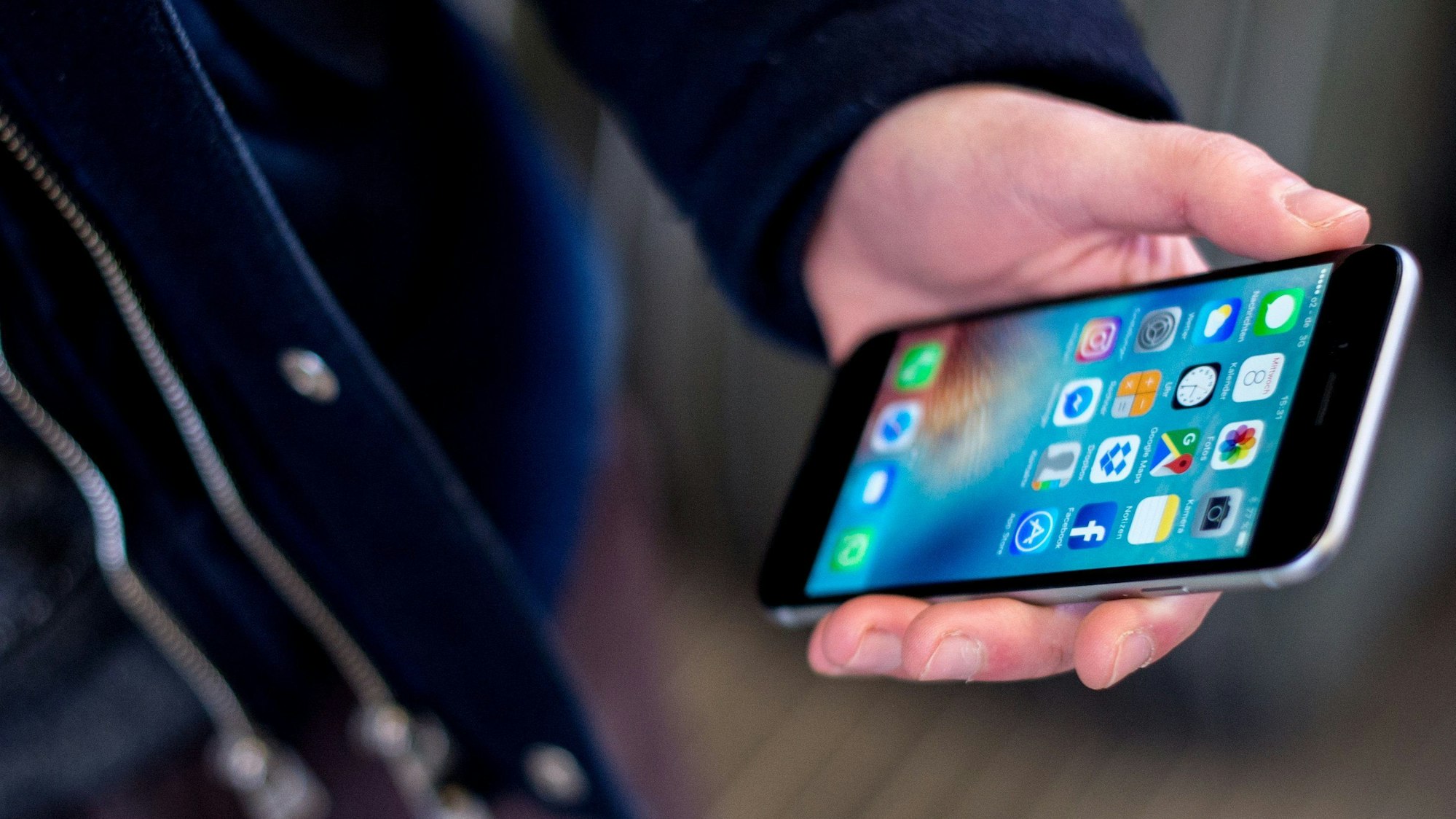 Das Symbolbild zeigt eine Hand, die ein Smartphone hält.