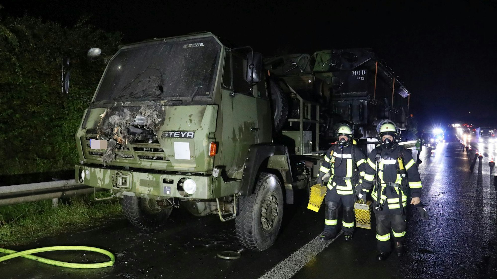 Feuerwehrleute neben einem Lkw in Militärfarbe