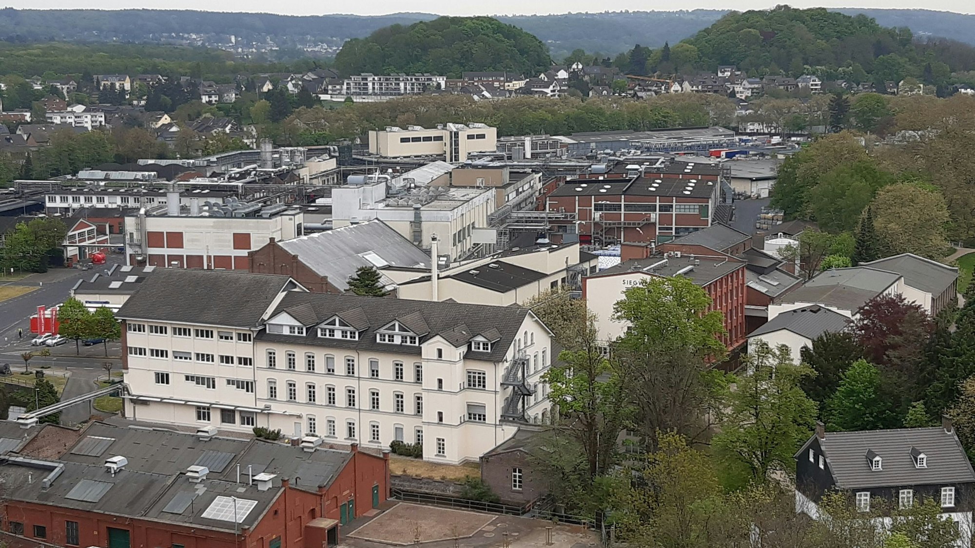 Ein Fabrikgelände mit älteren und neueren Gebäuden aus der Vogelperspektive