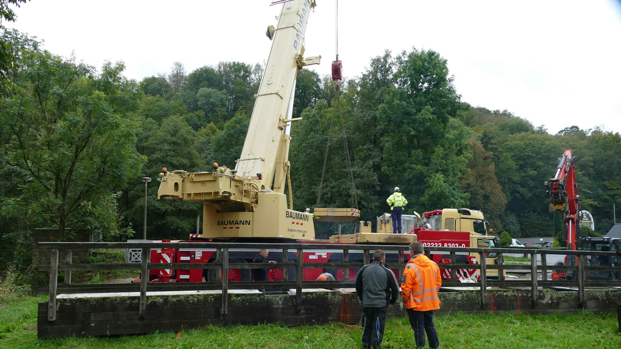 Ein Autokran steht hinter Teilen einer Brücke.