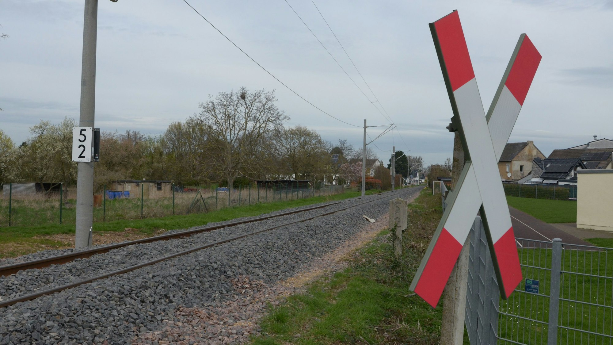 Das Bild zeigt eine Eisenbahnstrecke, im Vordergrund hängt ein Andreaskreuz.