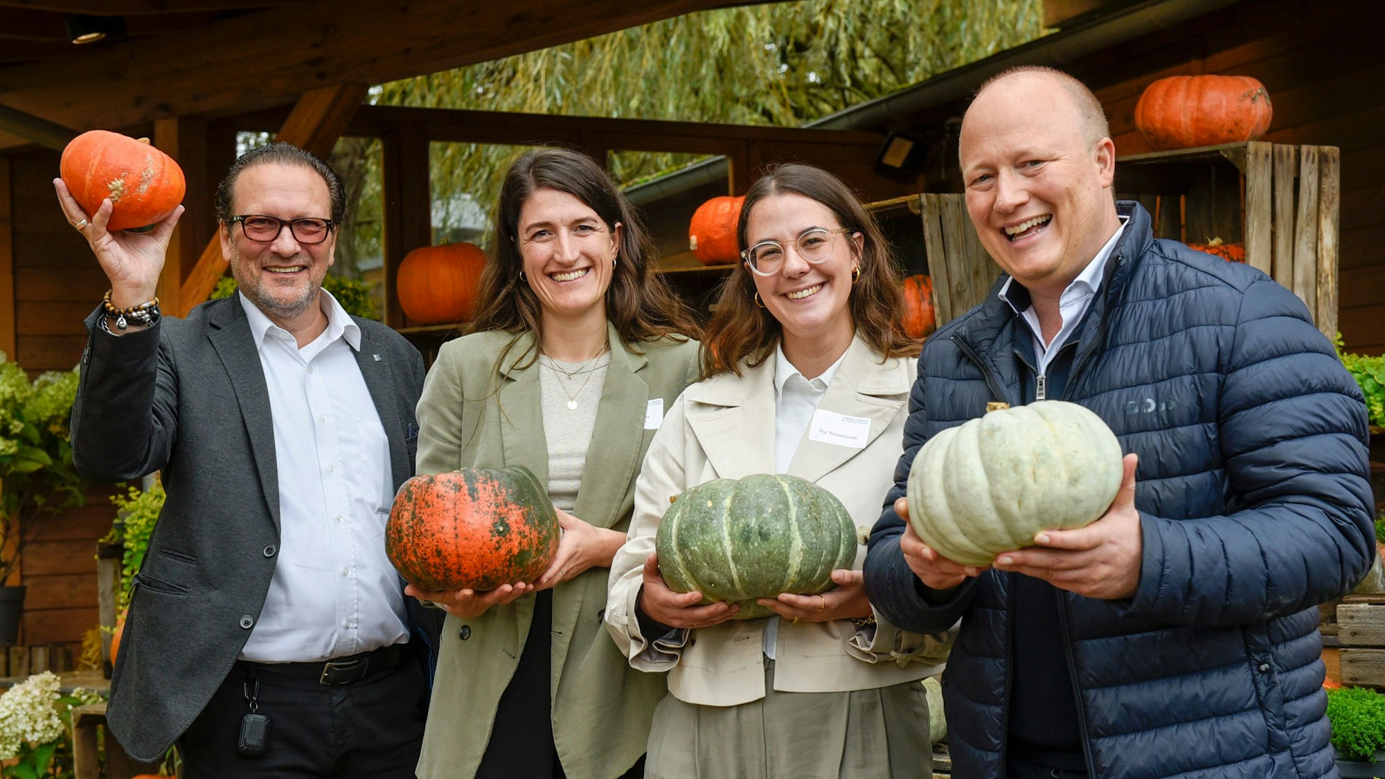 Das Foto zeigt zwei Männer und zwei Frauen, die Kürbisse in den Händen halten.