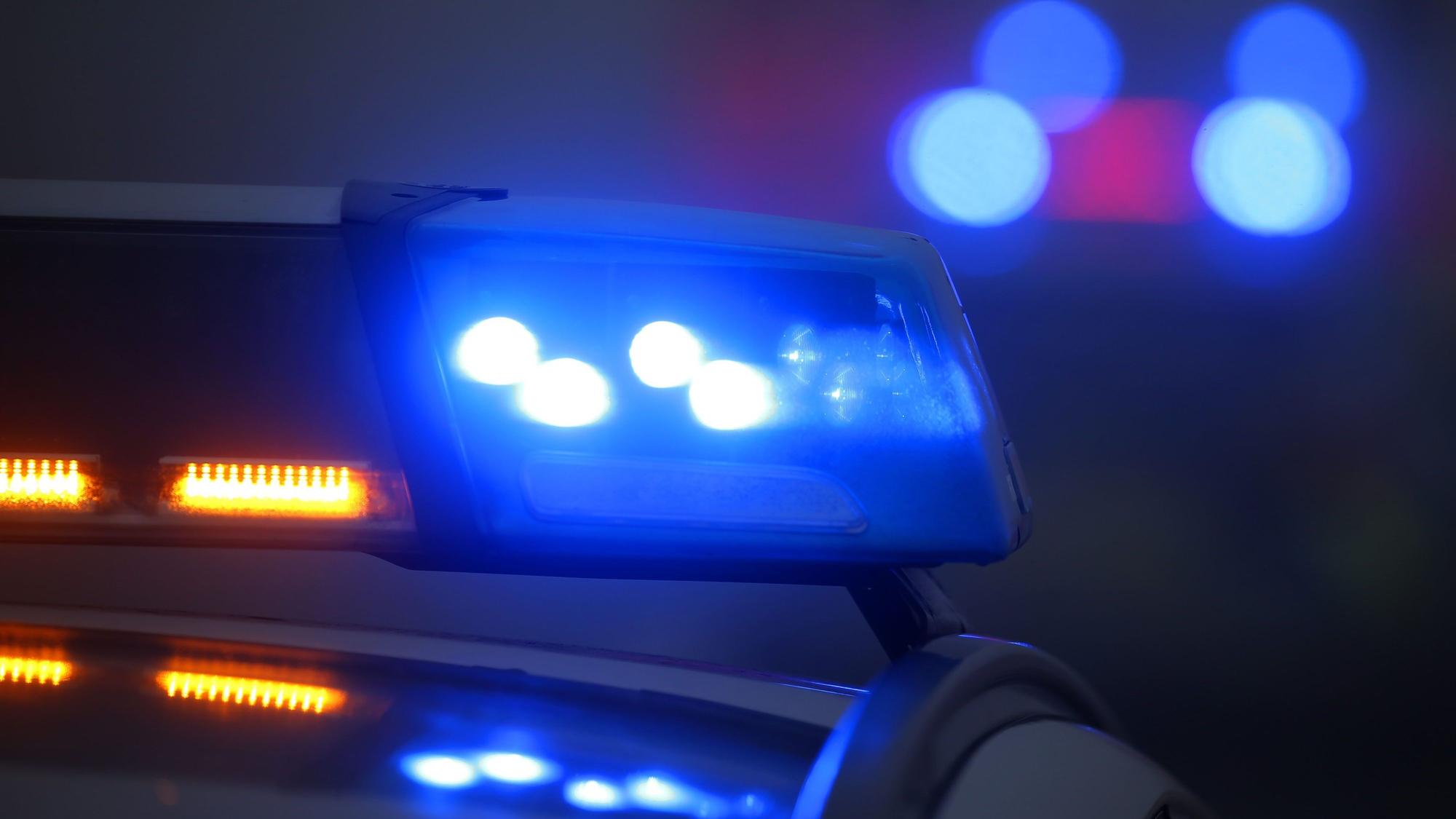 Ein Polizeiauto mit eingeschaltetem Blaulicht steht an einer Unfallstelle.