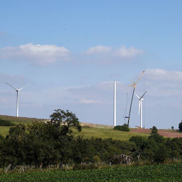 Auf einem Hügel bei Heimbach-Vlatten sind drei Windenergieanlagen zu sehen. Von einer vierten steht der Turm, mithilfe eines Krans wird daran gearbeitet.