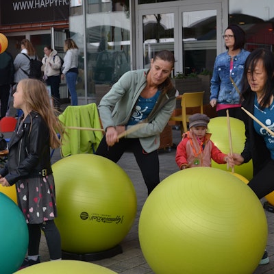 Kinder und Erwachsene trommeln auf Gymnastikbälle ein.
