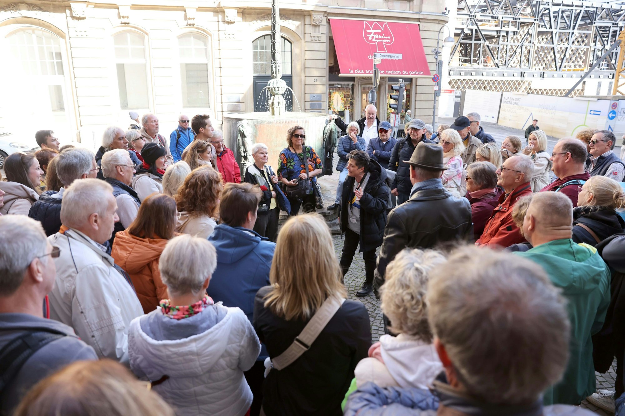 Menschen hören beim Tag der kölschen Sprache einer Stadtführerin zu.