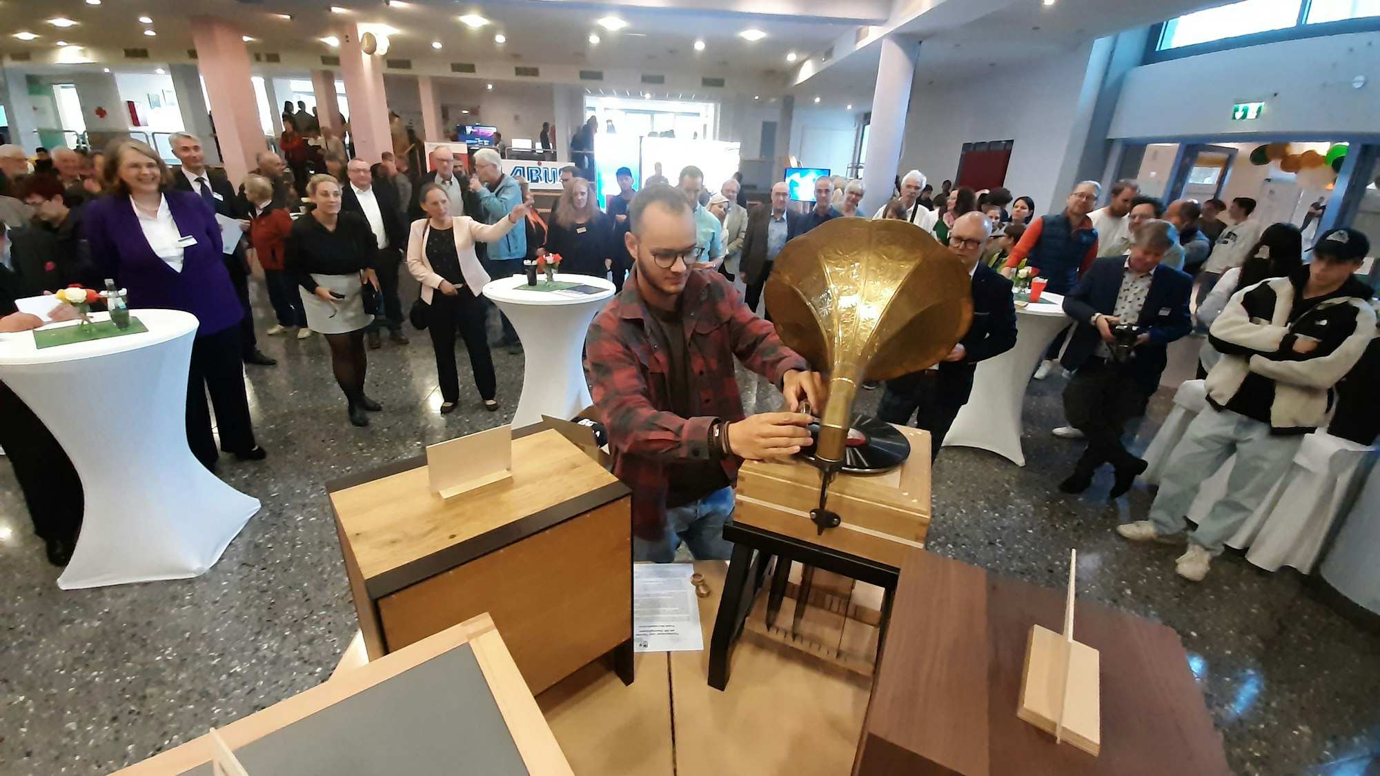 Ein junger Mann präsentiert den hölzernen Korpus eines Grammophons.