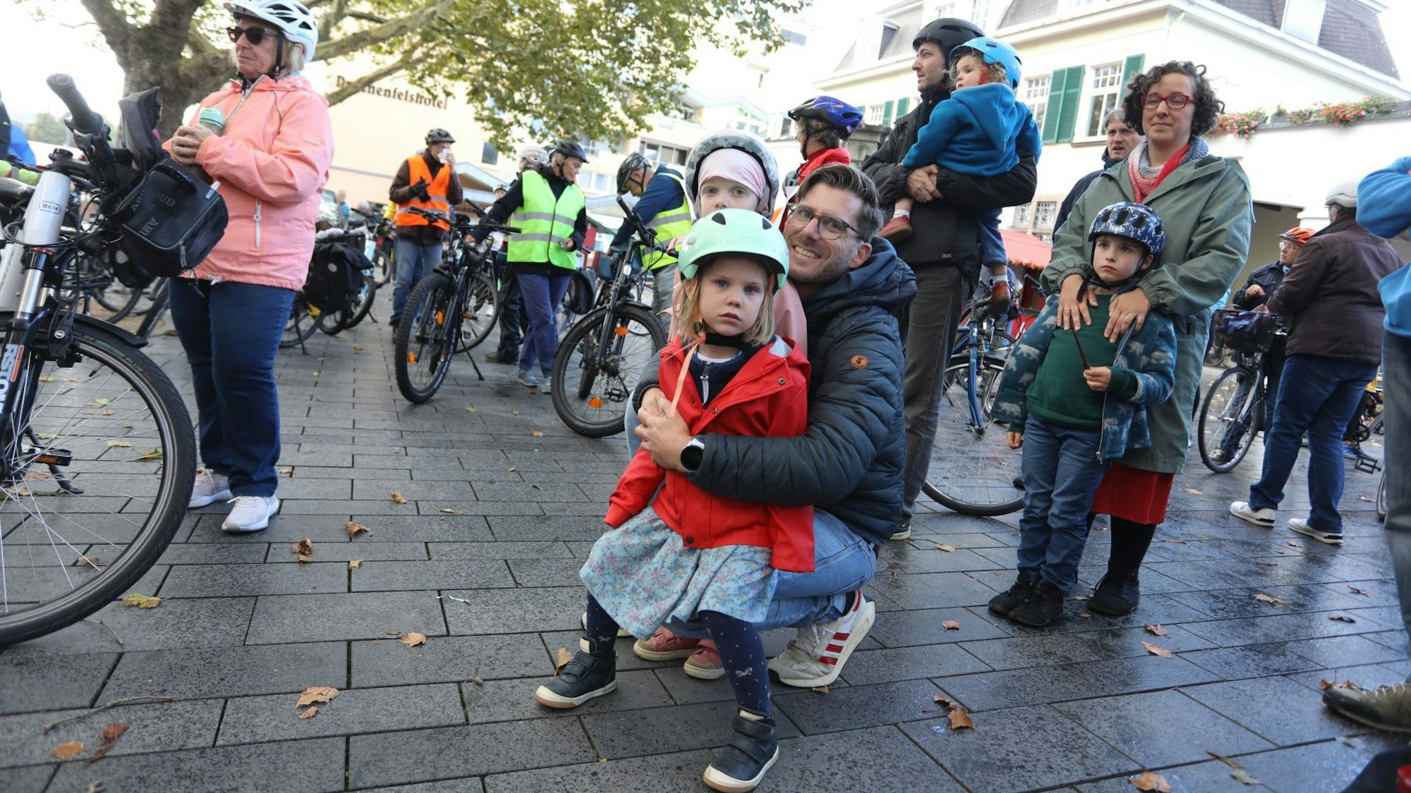 Mehrere Fahrradfahrende stehen auf dem Vorplatz des Rathauses in Königswinter, darunter auch eine Familie mit zwei kleinen Kindern.