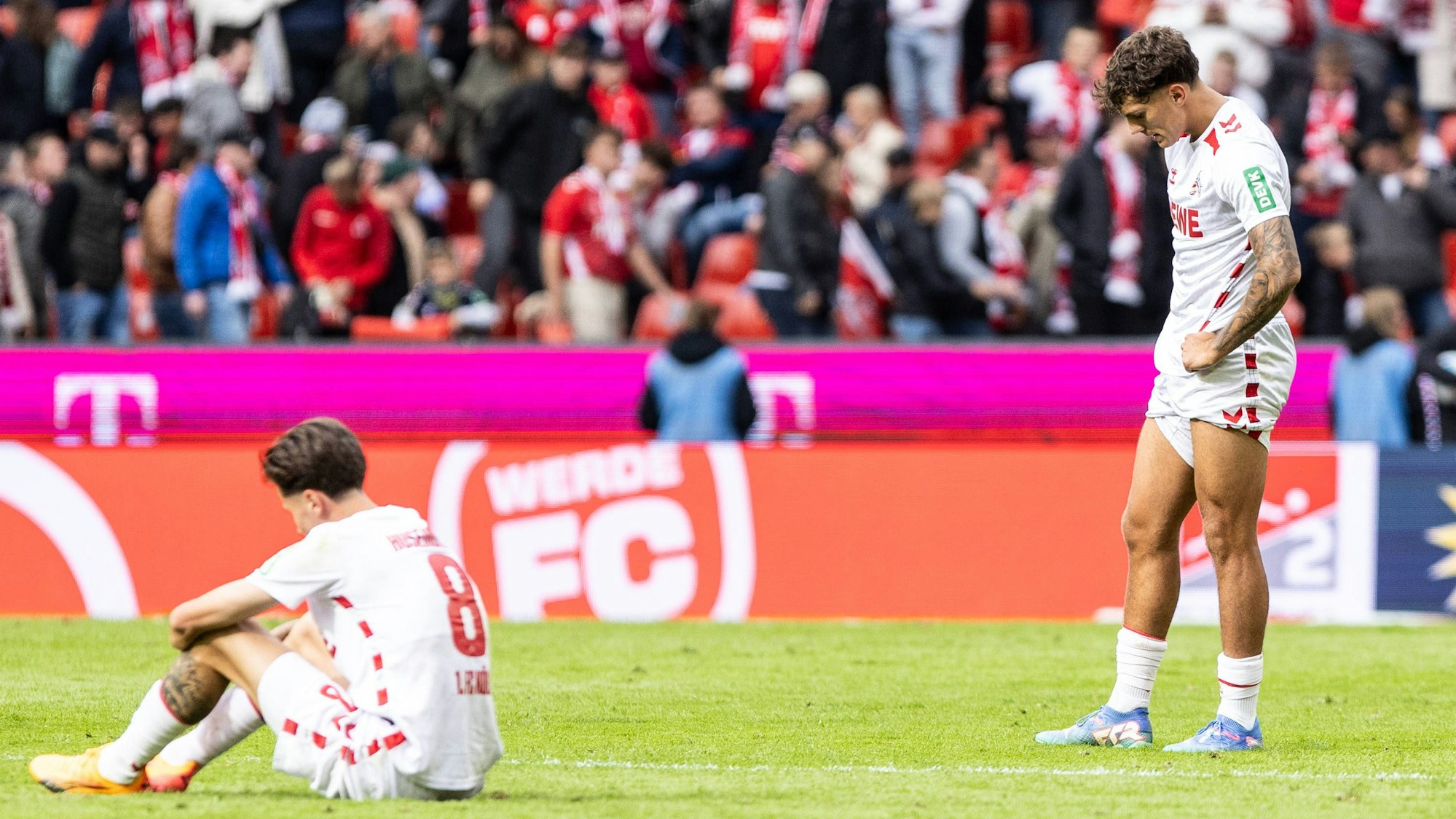Denis Huseinbasic (l) sitzt auf dem Rasen und teilt seine Enttäuschung nach dem 4:4 gegen Karlsruhe mit Julian Pauli.