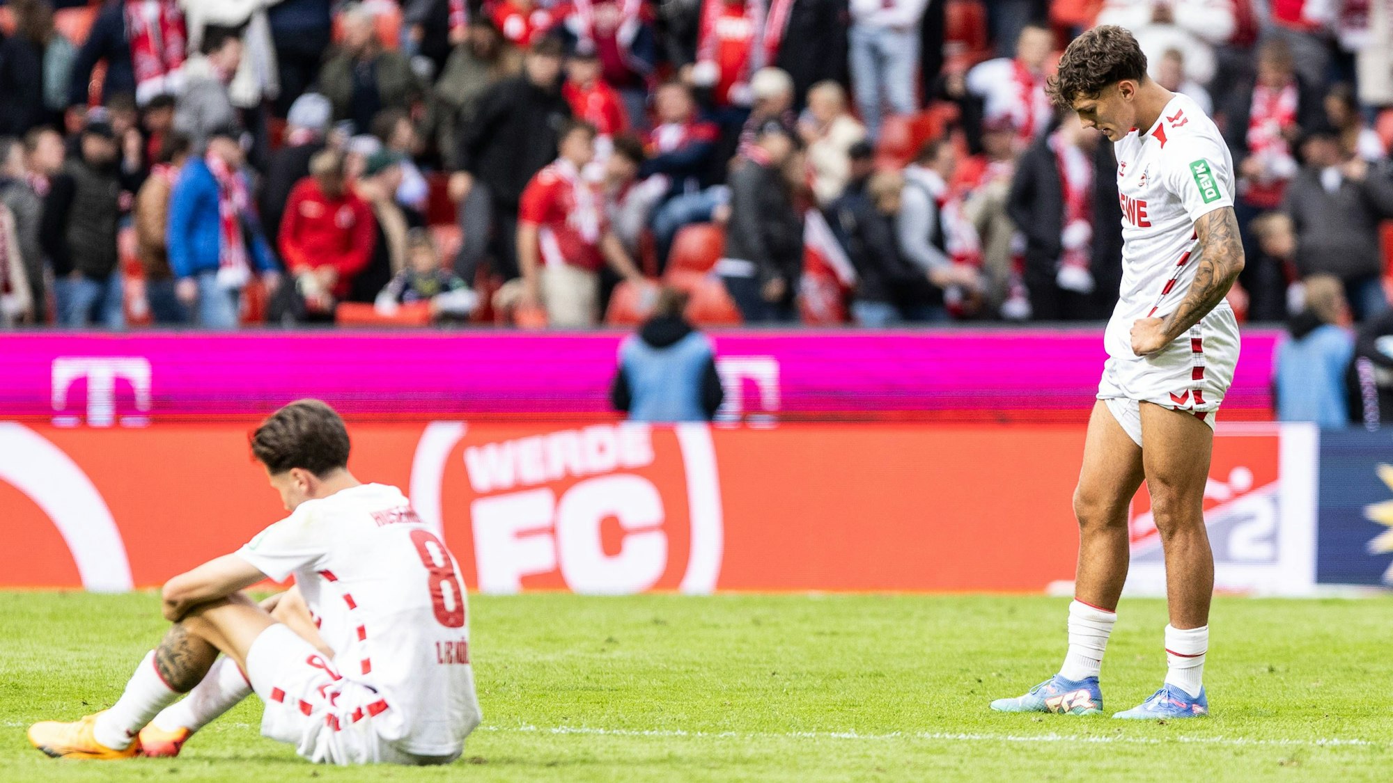 Denis Huseinbasic (l) sitzt auf dem Rasen und teilt seine Enttäuschung nach dem 4:4 gegen Karlsruhe mit Julian Pauli.
