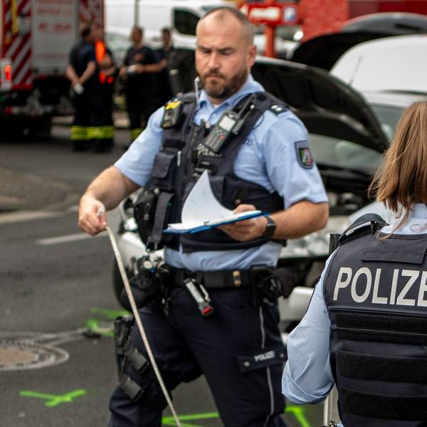 Das Bild zeigt eine Polizistin und einen Polizisten bei der Aufnahme eines Verkehrsunfalls in Euskirchen. Sie haben beide ein Maßband in der Hand.