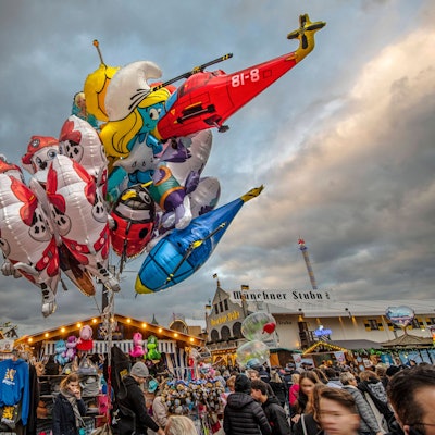 Luftballons leuchten vor wolkenschwerem Himmel über dem Oktoberfest in München.