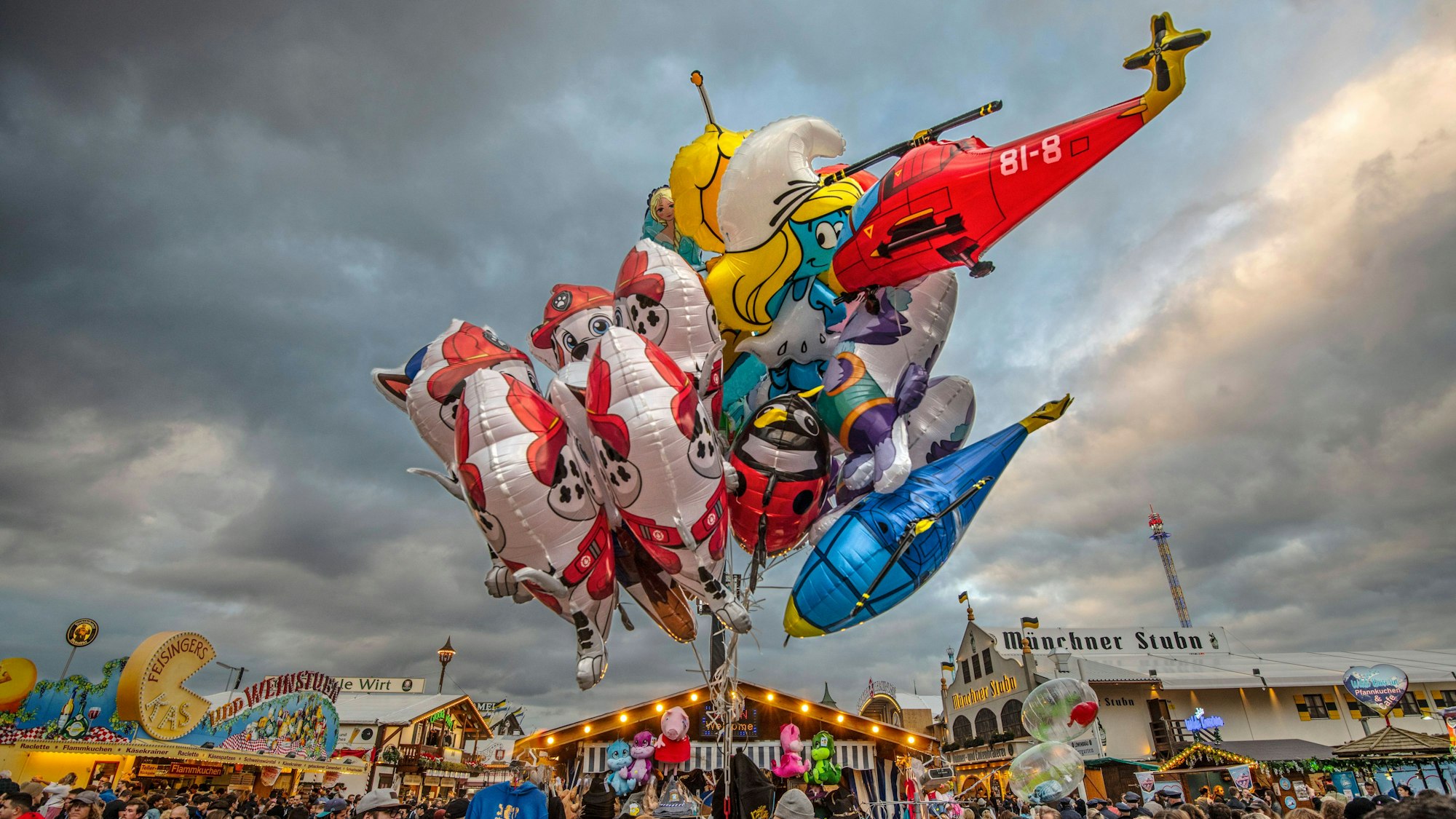 Luftballons leuchten vor wolkenschwerem Himmel über dem Oktoberfest in München.
