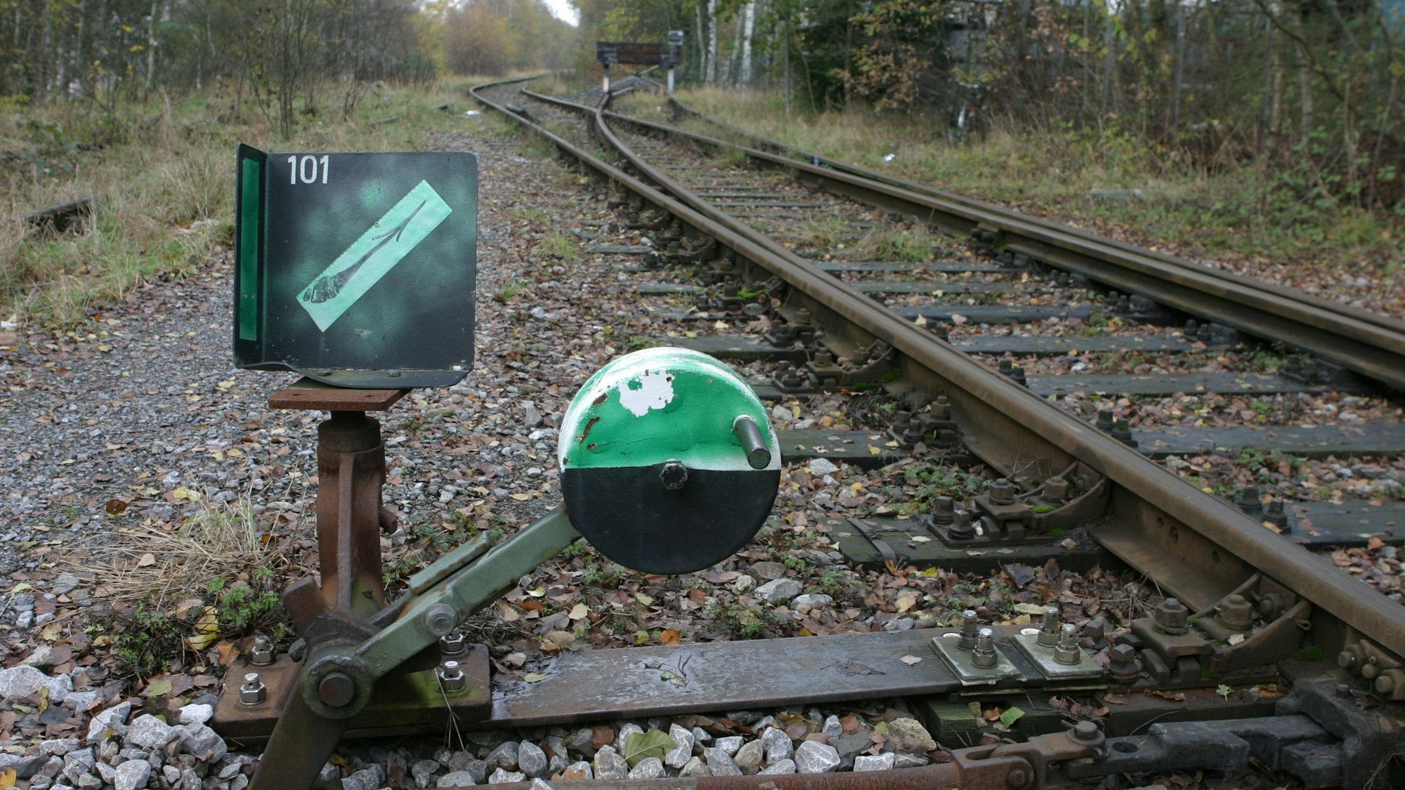 Grünes Zeichen vor den Gleisen des alten Bahndamms.