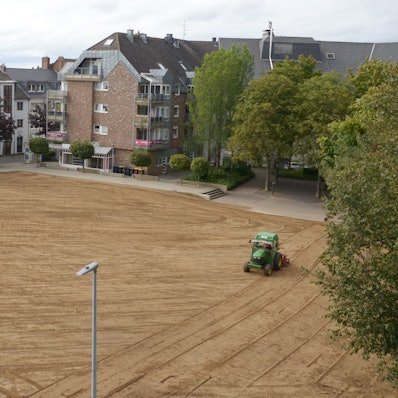 Ein Traktor glättet eine Brachfläche in der Innenstadt.