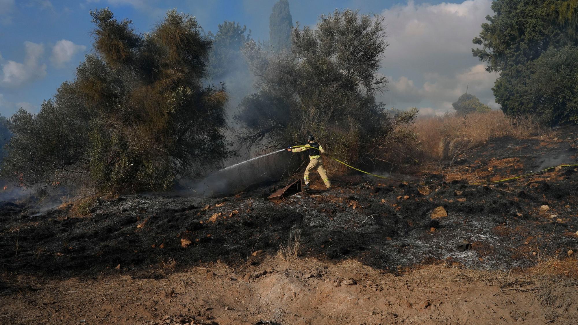Nahariya: Ein israelischer Feuerwehrmann arbeitet daran, ein Feuer zu löschen, nachdem eine aus dem Libanon abgefeuerte Rakete in der Nähe von Nahariya im Norden Israels eingeschlagen ist.