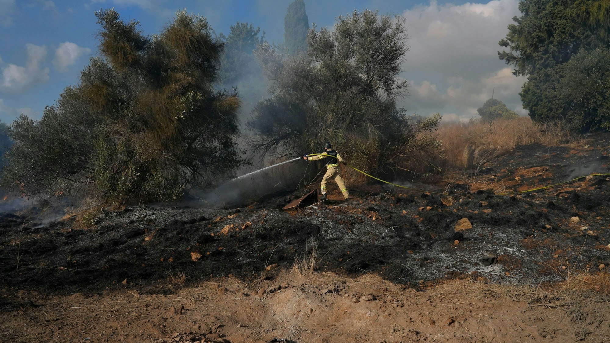 Nahariya: Ein israelischer Feuerwehrmann arbeitet daran, ein Feuer zu löschen, nachdem eine aus dem Libanon abgefeuerte Rakete in der Nähe von Nahariya im Norden Israels eingeschlagen ist.