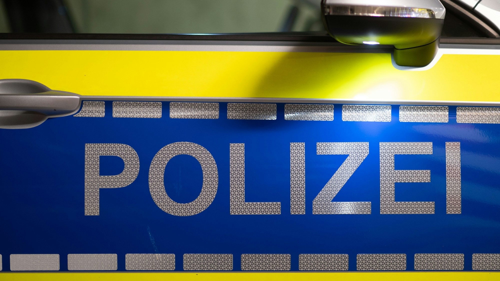 Das Wort Polizei ist auf der Tür eines Polizeiautos zu lesen.