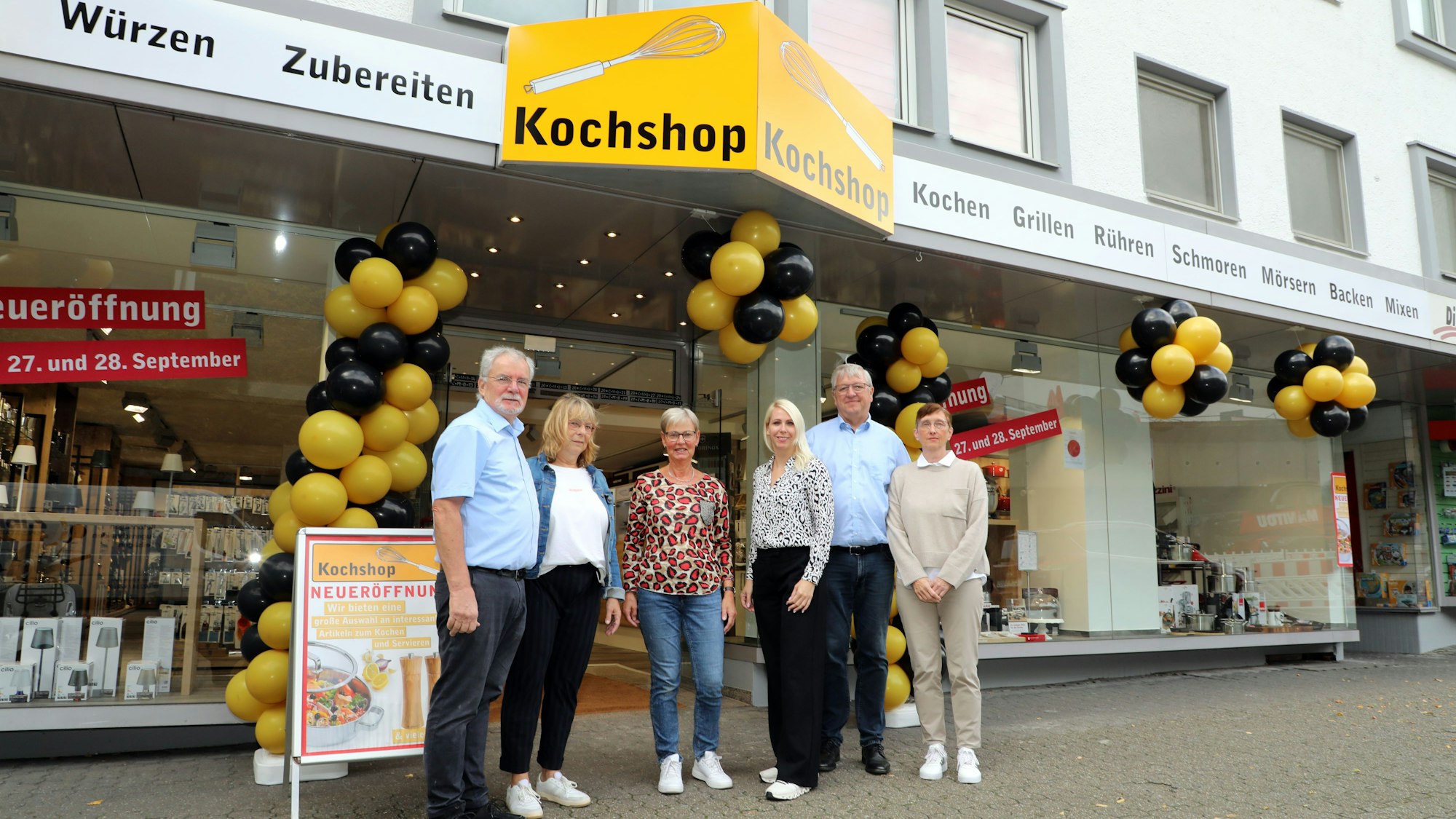 Georg Daubenbüchel, Maria Daubenbüchel, die alten und neuen Mitarbeiterinnen Christine Müller und Susan Hübner sowie die Inhaber der Kochshop-Handelskette Stefan und Renate Schmitz aus Solingen stehen vor der neuen Kochschop-Filiale an der Schloßstraße 68 in Bensberg.