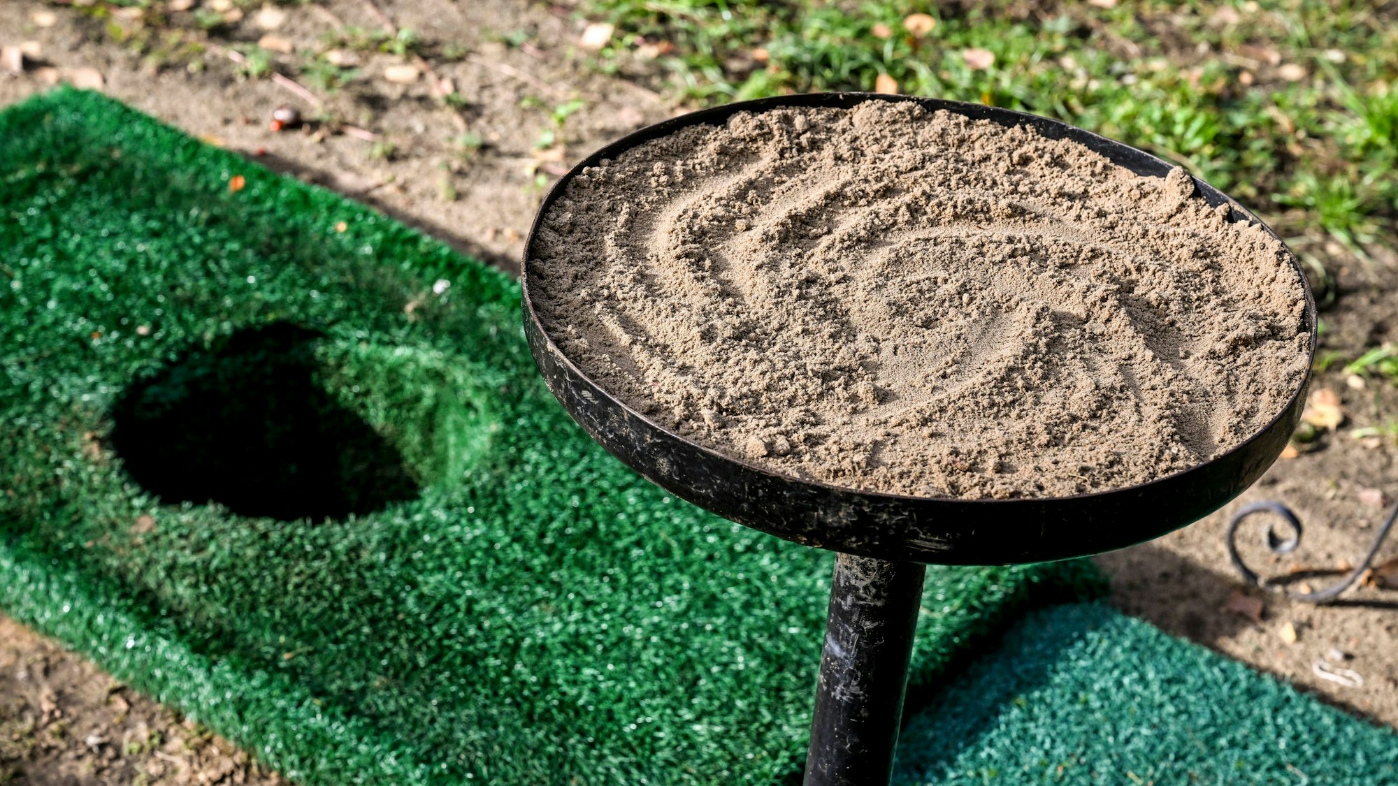 Ein Loch in der Erde und eine Schale mit Erde sind für eine Urnenbeisetzung  vorbereitet.