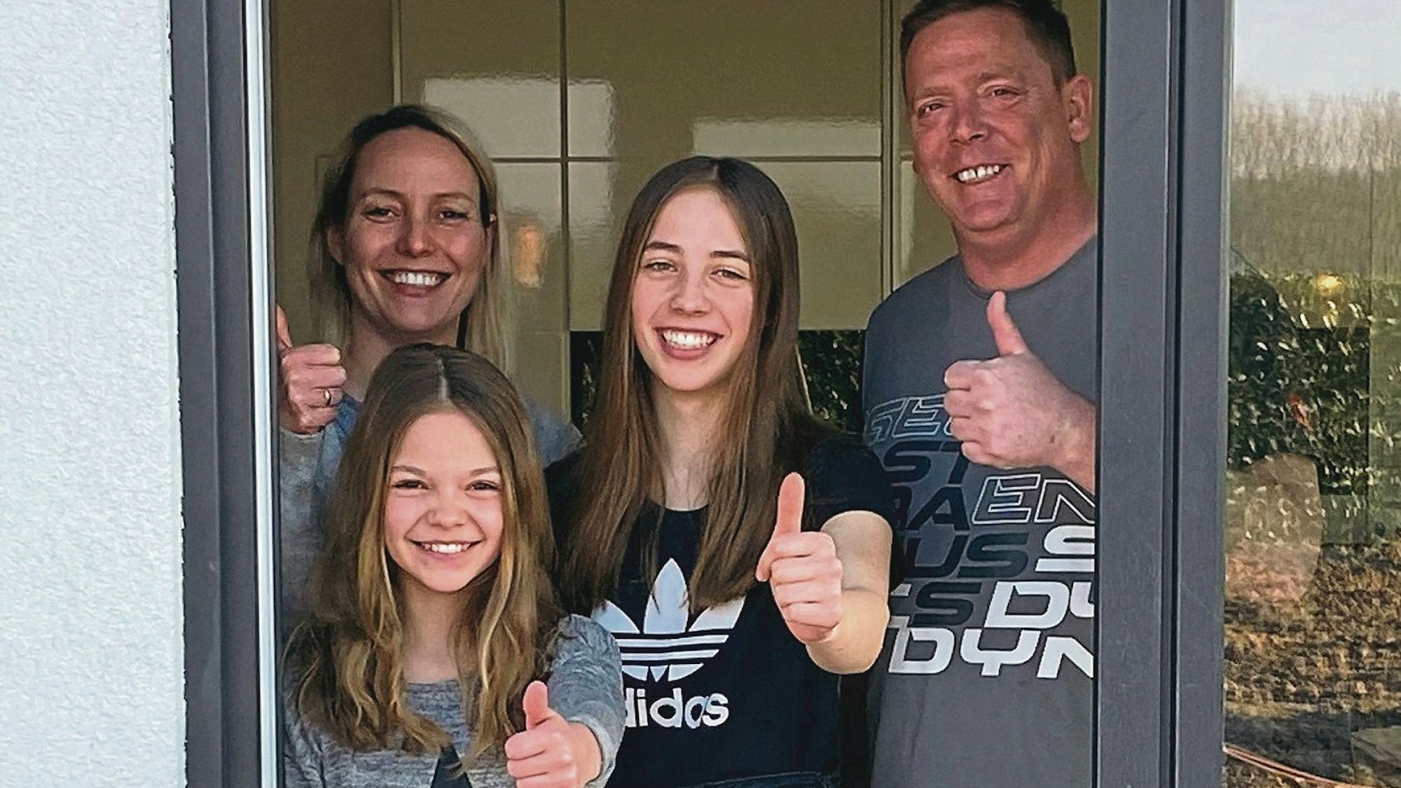 Familie Peters aus Steinenbrück steht in der Terrassentür und streckt den Daumen nach oben.
